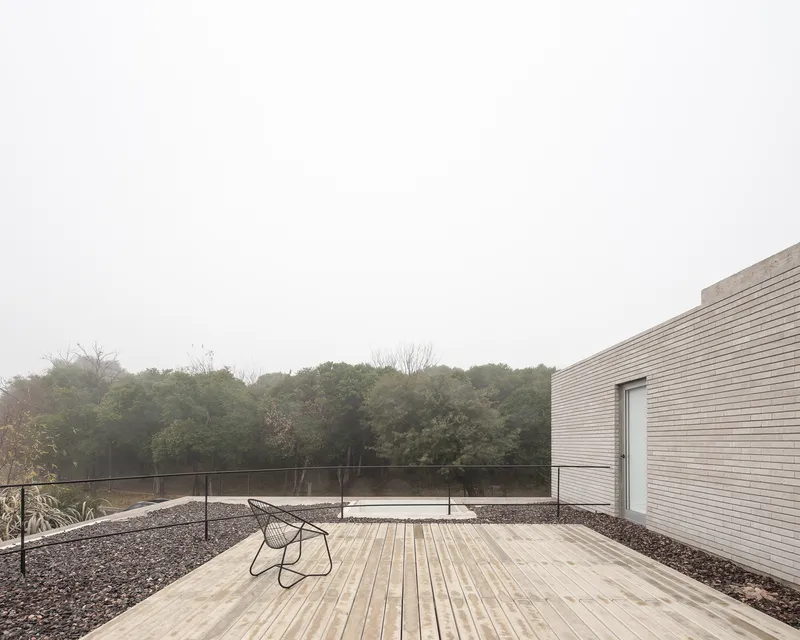 Rooftop terrace: timber deck, wire chair, gravel border, reserve canopy stretching to the horizon