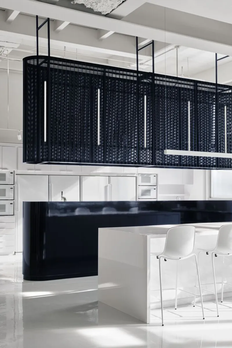 Hanging black mesh enclosure with vertical pendant lights above kitchen island and bar seating