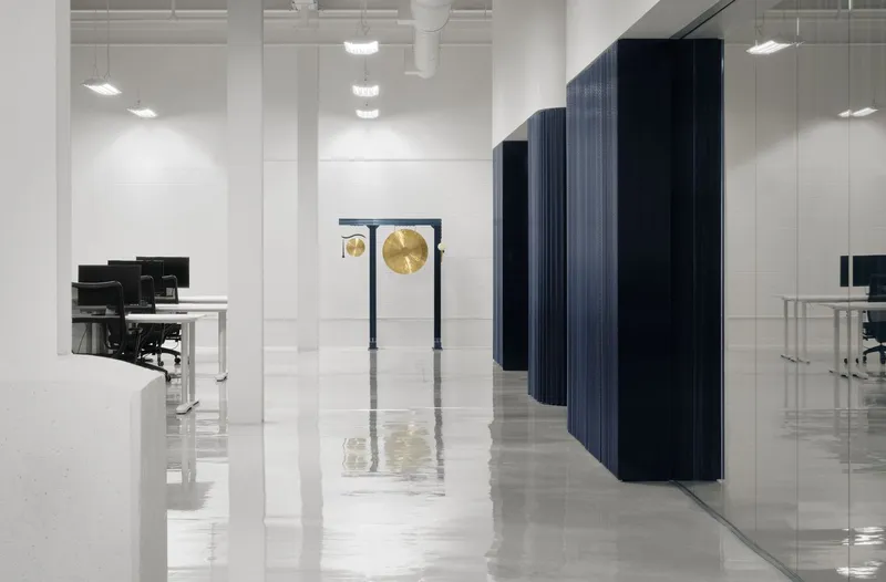Office floor with freestanding dark ribbed partitions creating corridors between workstations on polished tile