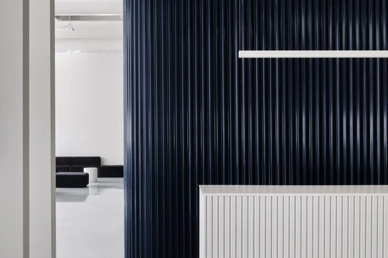 White fluted reception counter with dark blue vertical panel wall and glimpse of office seating beyond