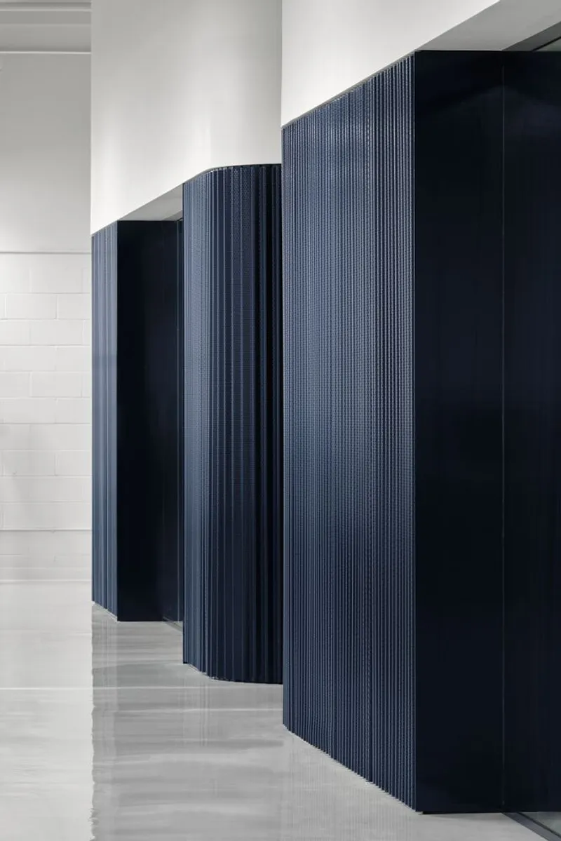 Detail of curved fluted blue panels alongside polished white floor and white column