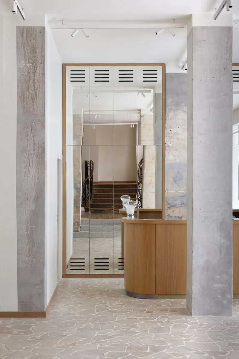 After: oak and concrete reception desk with ventilation grilles, staircase beyond