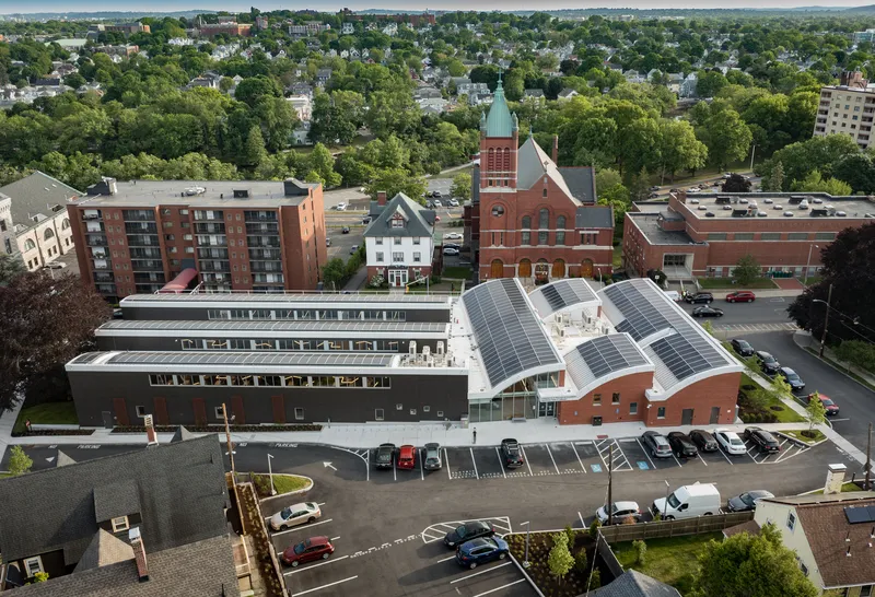Aerial view of the library with undulating metal roof and solar panels adjacent to a parking lot