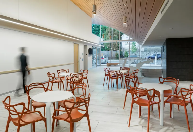 Cafe seating area with orange chairs under a wood slat ceiling and clerestory windows
