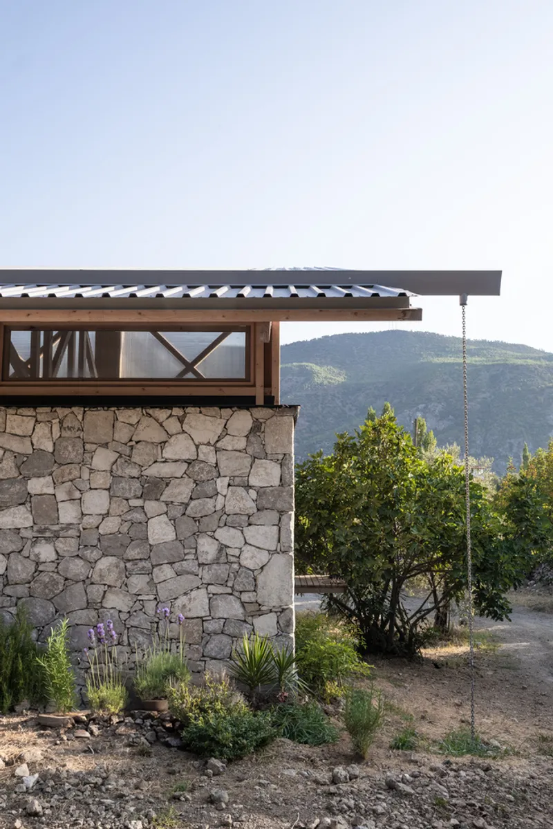Stone wall with timber framing and tiled roof overhang framed by lavender and hillside vegetation