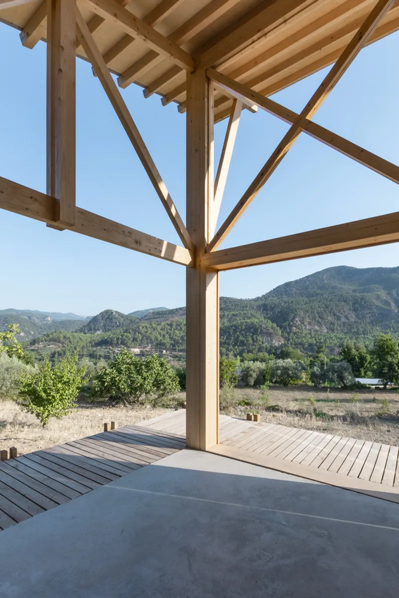 Covered timber porch with radiating rafters opening onto wood deck with mountain views