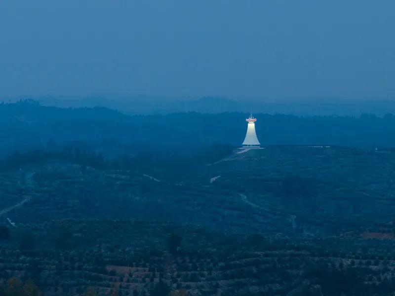 Tower at blue hour: the glowing white form seen from kilometres away, a beacon on the dark hilltop