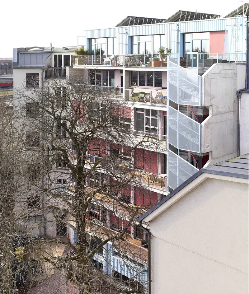 Courtyard elevation revealing multiple residential levels with balconies, bicycles, and planted terraces in winter