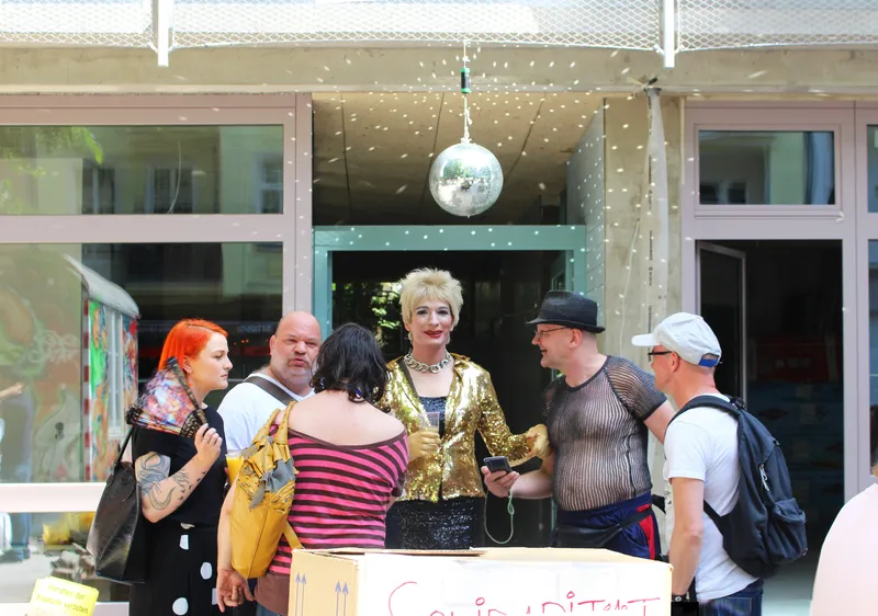 Street view of the storefront entrance with disco ball and visitors gathered outside in daylight