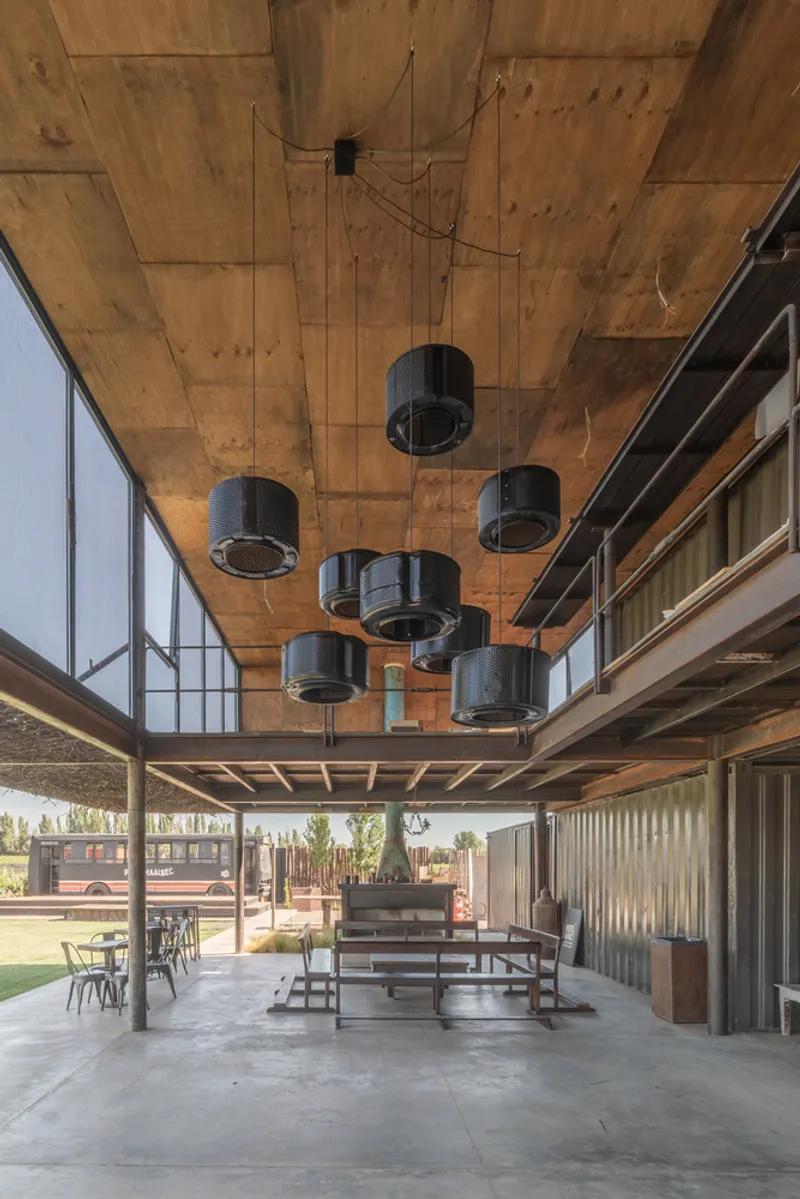 Covered patio with exposed timber ceiling, suspended cylindrical heaters and corrugated metal wall partitions