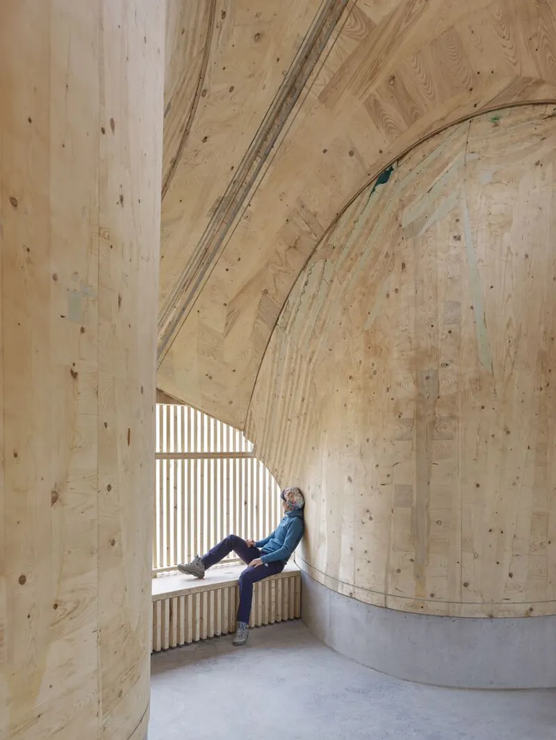 Interior window alcove with timber vault ceiling and seated figure silhouetted against slatted screen