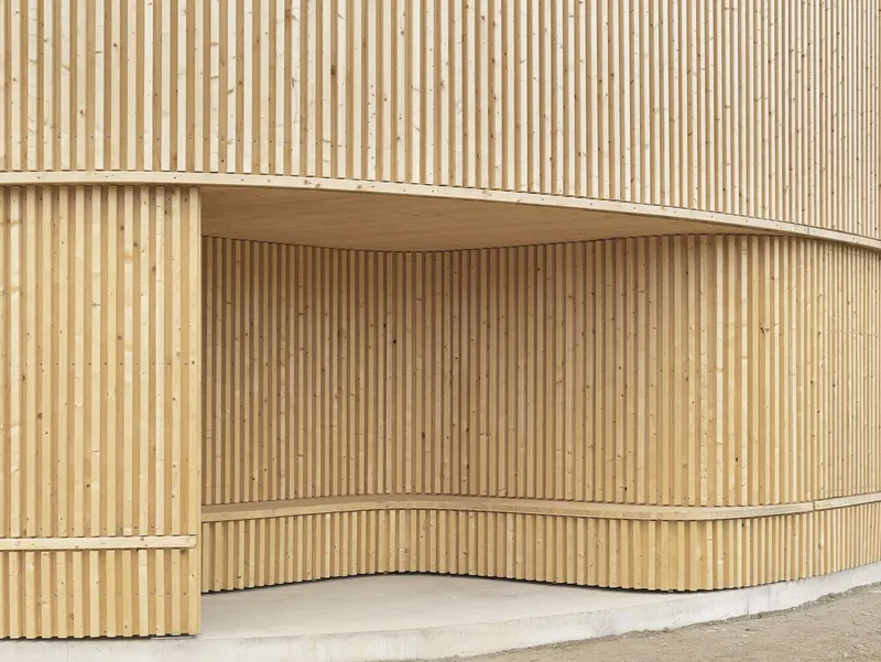 Close-up of the curved timber slat wall forming a recessed alcove above a concrete plinth