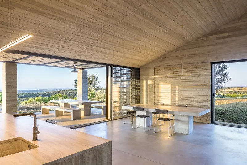 Living and dining area with sliding glass doors opening to a terrace overlooking olive groves