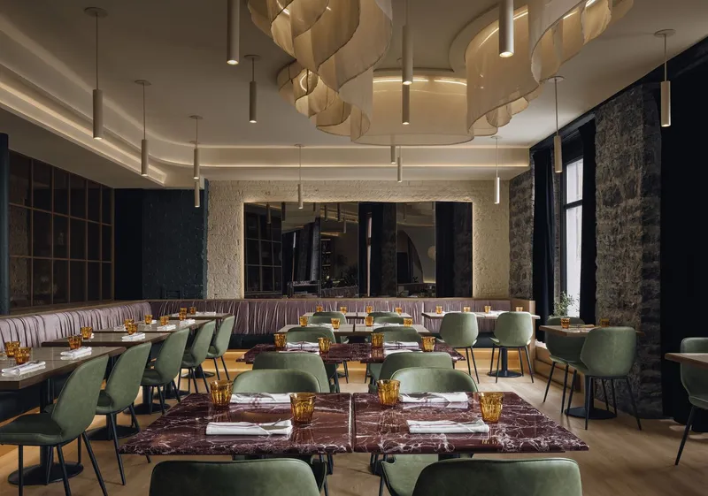 Dining room interior with spiraling layered pendant fixtures and set tables beneath a cove-lit ceiling
