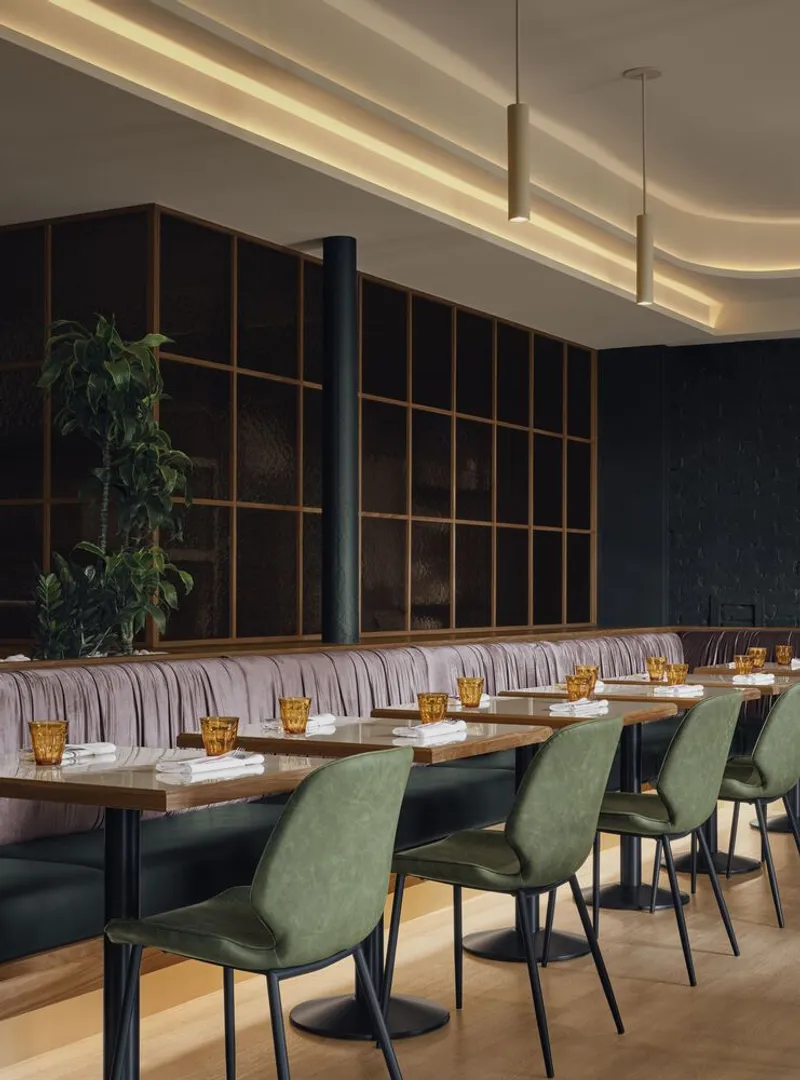 Dining area with timber grid partition, striped banquette seating, and pendant lights under curved ceiling