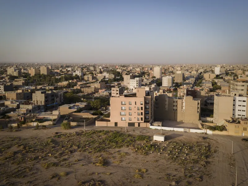 Drone view of the beige brick tower rising from scrubland dotted with vegetation