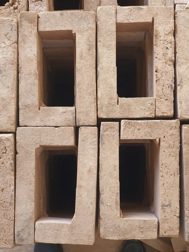 Close-up of precast concrete blocks with recessed openings stacked in an irregular pattern