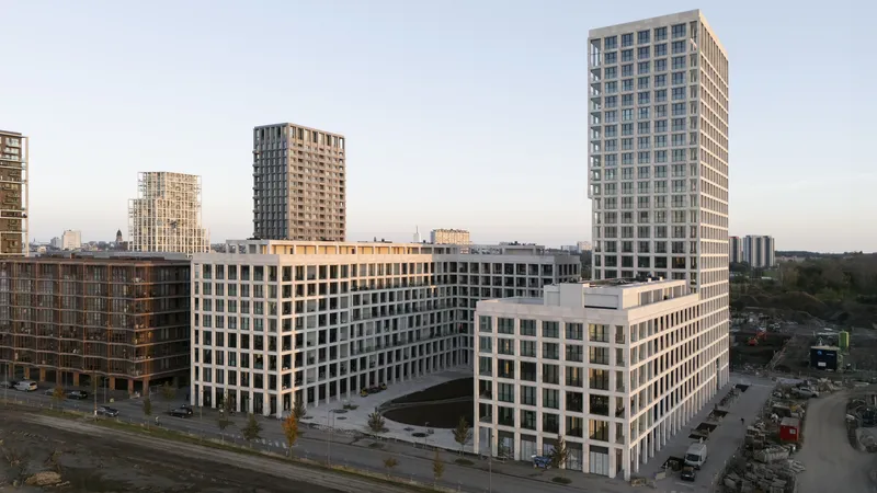 Aerial view of the mixed-use development with multiple residential towers rising above a podium at dusk