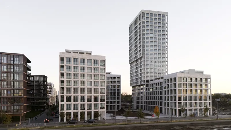 Street view showing three residential towers with gridded facades in the early evening light