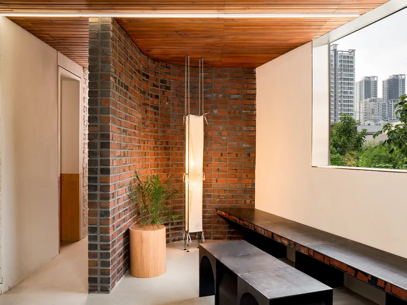 Corner seating nook with exposed brick wall and timber ceiling overlooking urban rooftops