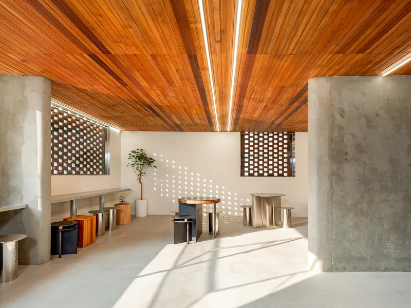 Interior view showing perforated brick screens casting dappled light across polished concrete floor