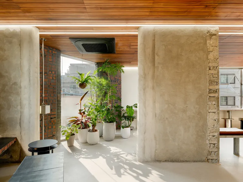 Concrete columns framing a collection of potted plants beneath a timber slat ceiling