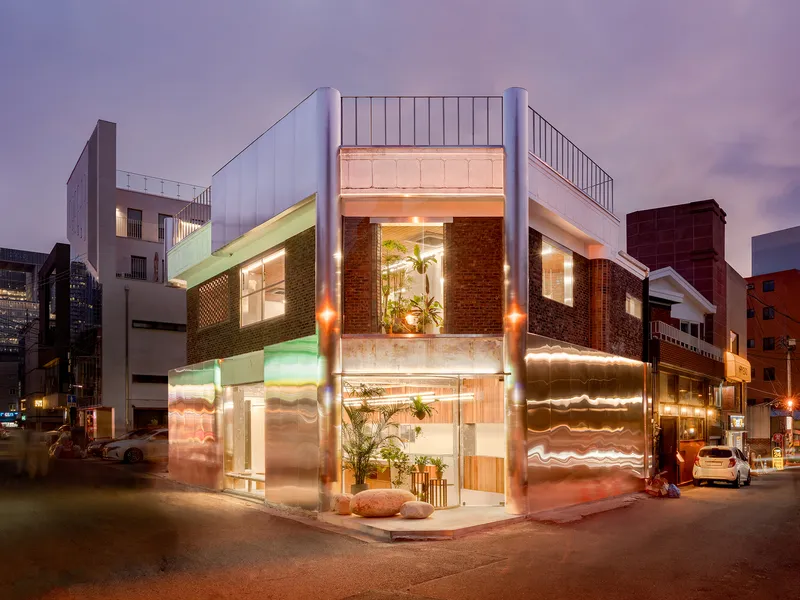 Corner facade at twilight showing brick cladding, glazed storefront and white parapet above