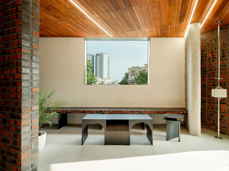 Upper room with timber slat ceiling, brick walls, and steel table beneath a picture window