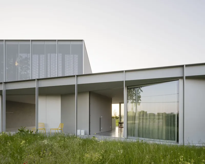 Corner detail of recessed terrace with sliding glass walls and angled translucent screen above in twilight