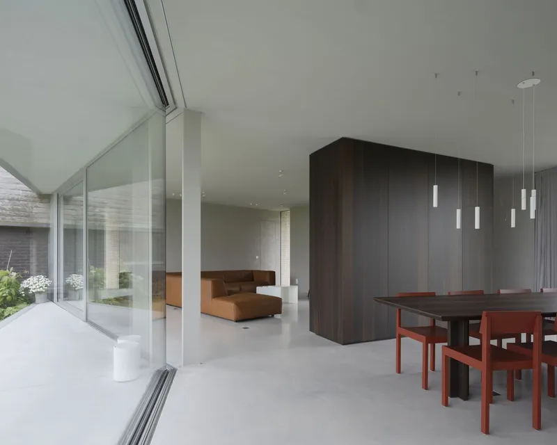 Interior view from terrace threshold showing dark timber volume dividing dining area from lounge with courtyard beyond