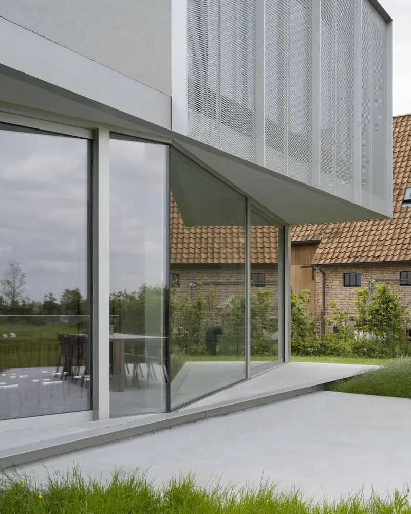 Sliding glass doors opening to a concrete terrace with a neighboring tiled-roof building reflected