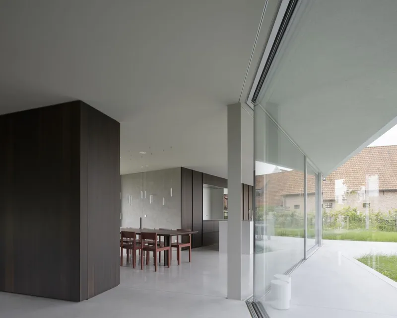 Open plan dining and kitchen space with dark timber joinery and full-height glazed doors to garden
