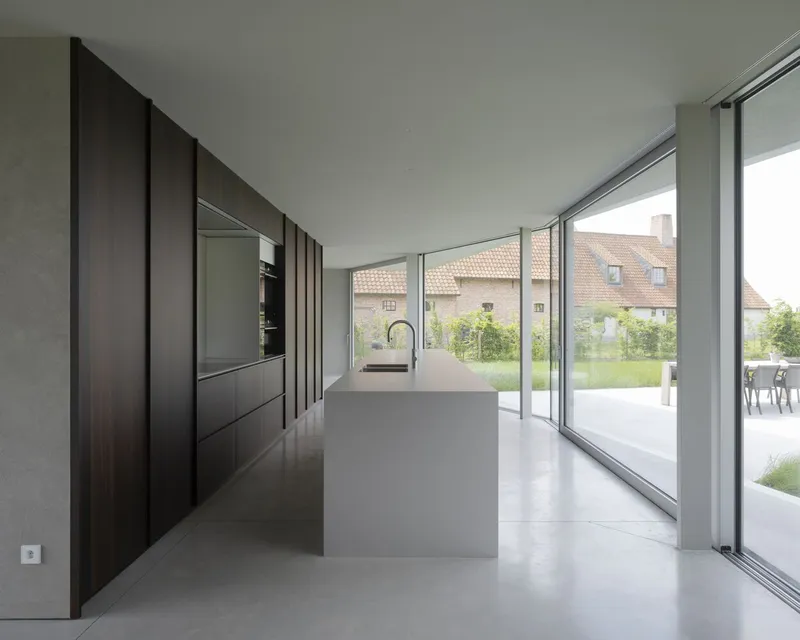 Kitchen with dark timber cabinetry and white island opening to garden terrace through sliding glass doors