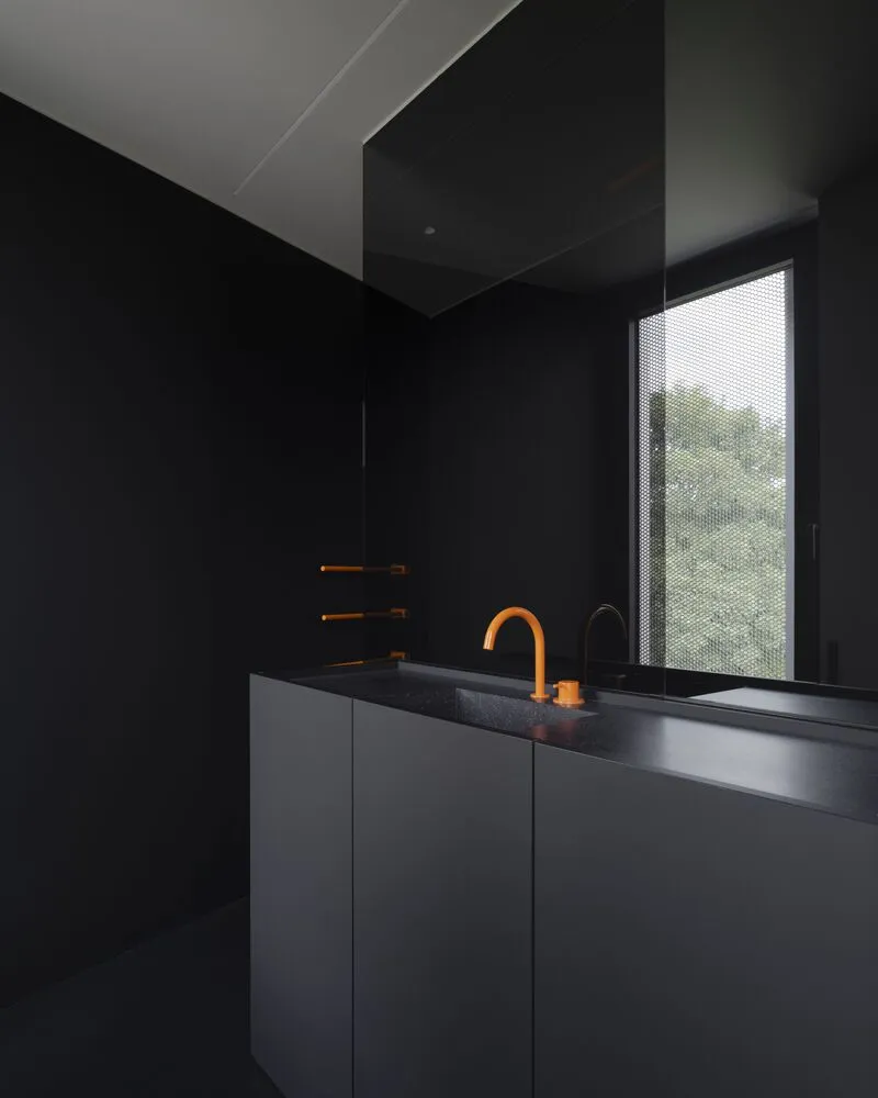 Bathroom vanity with terracotta faucet and towel rail beside perforated window screen overlooking greenery