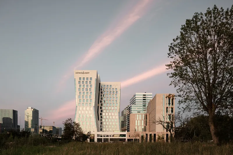 Distant view of the twin towers across an open field under a rainbow at dusk