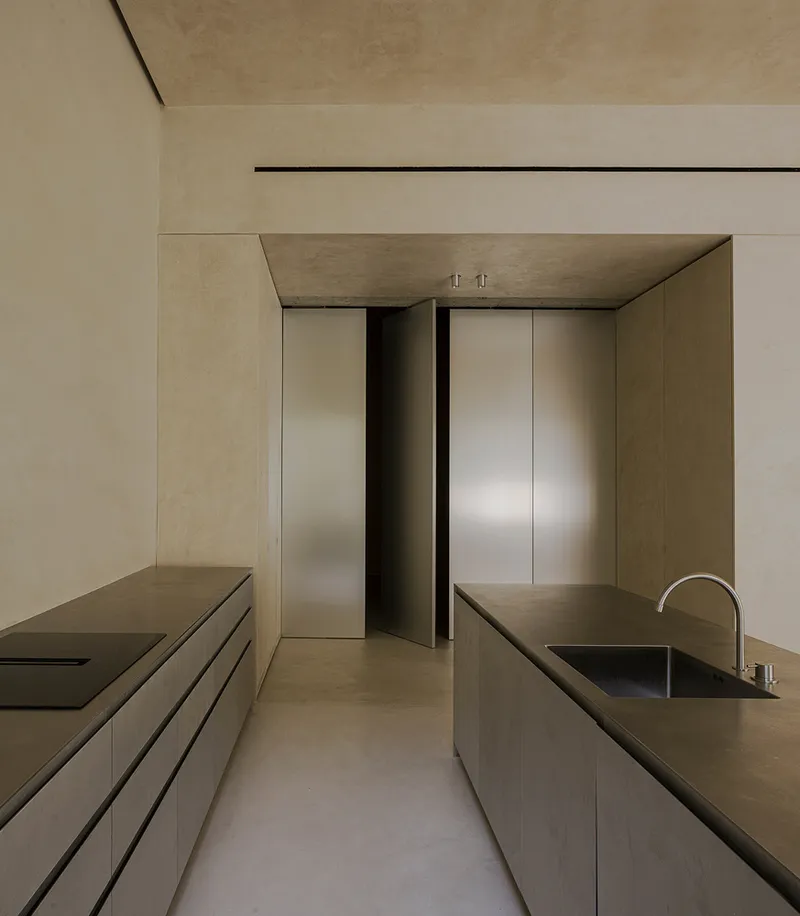 Galley kitchen with brushed metal counters, recessed lighting and tall metal door panels at the end