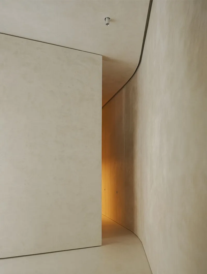 Curved corner passage with concealed lighting revealing a transition between plaster surfaces