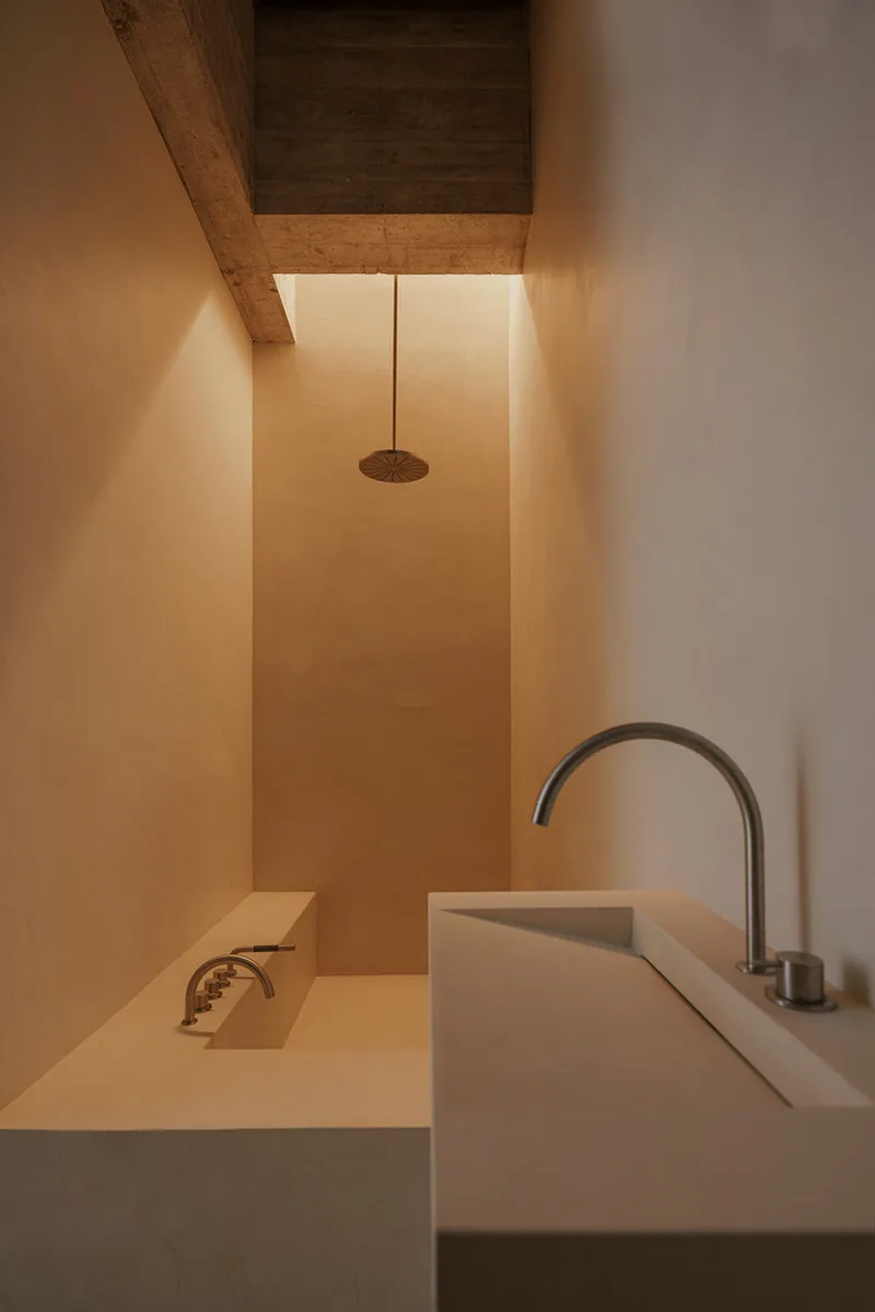 Bathroom with rectangular sink and rainfall shower head beneath a timber-lined skylight slot