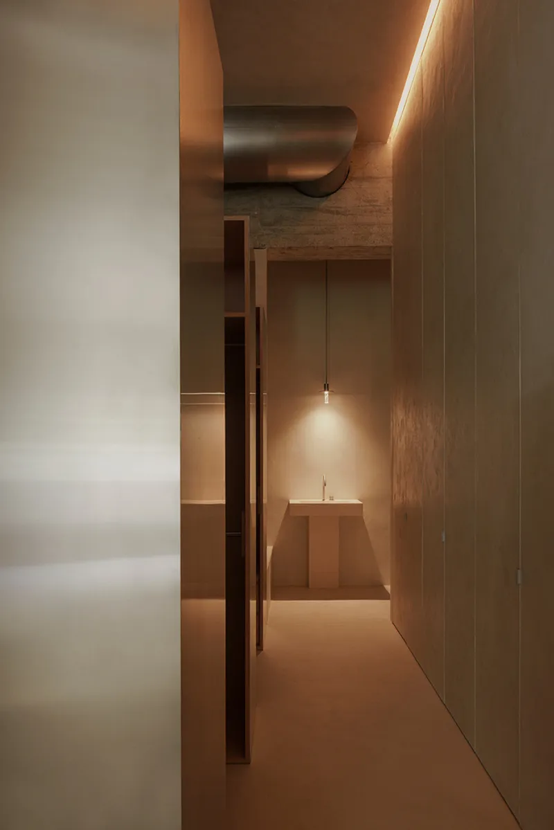 Corridor view toward a stepped altar-like platform illuminated by a single pendant light
