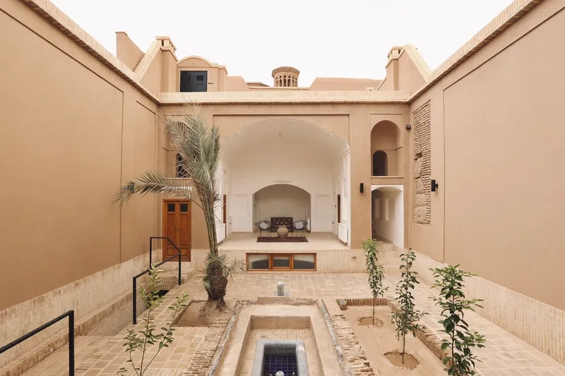 Courtyard facade with deep arched iwan, exposed brick wall detail and young plantings