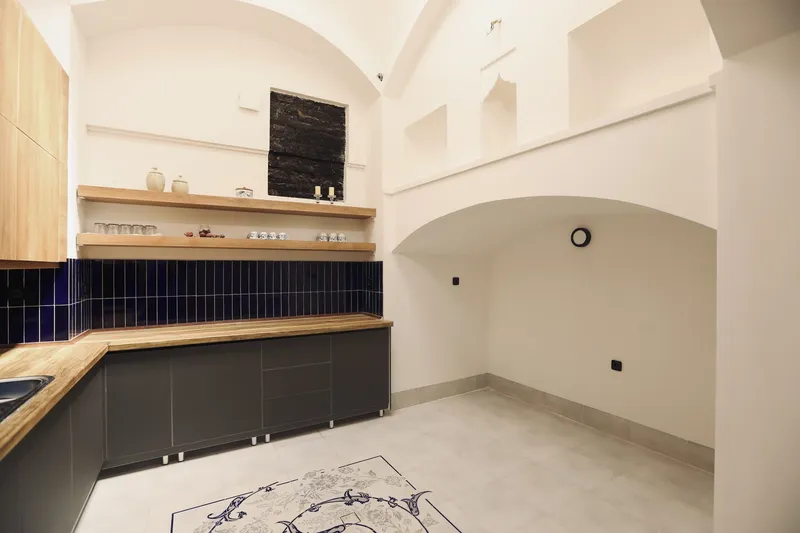 Kitchen with timber countertops, dark tile backsplash and vaulted archway leading to adjacent room