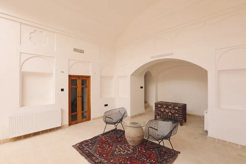 Interior room with arched recesses, raised paneling, and wire chairs on patterned rug