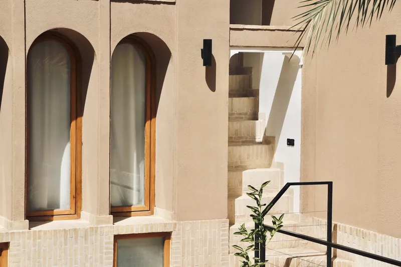 Close-up of arched windows with timber frames and metal railing beside planted greenery