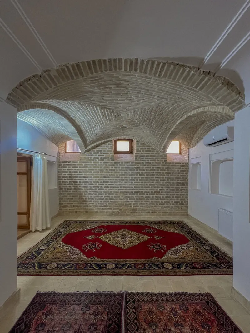 Interior hall with radial brick vault ceiling and three small square windows in the end wall