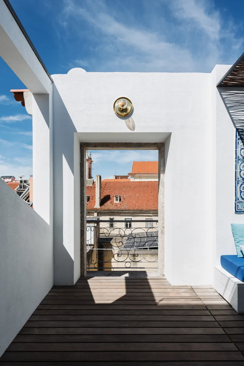 Rooftop terrace with timber decking framing a view of orange-tiled rooftops beneath clear blue sky