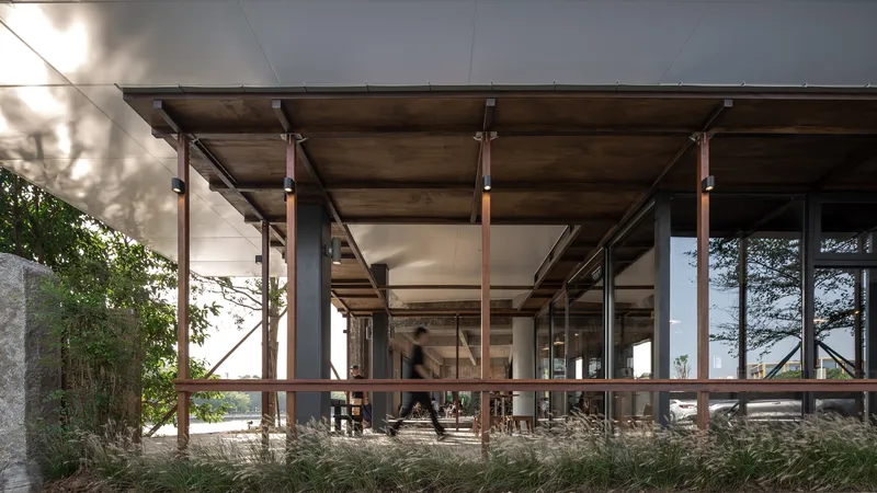 Through the pavilion: posts receding in perspective, figure walking, river beyond, dappled afternoon light
