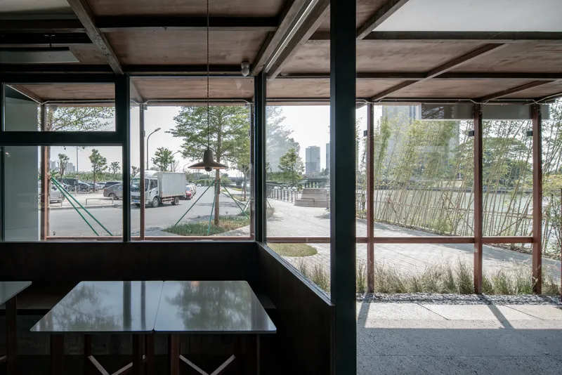 From inside: framed timber columns looking out to the street, parked vehicles, timber bench