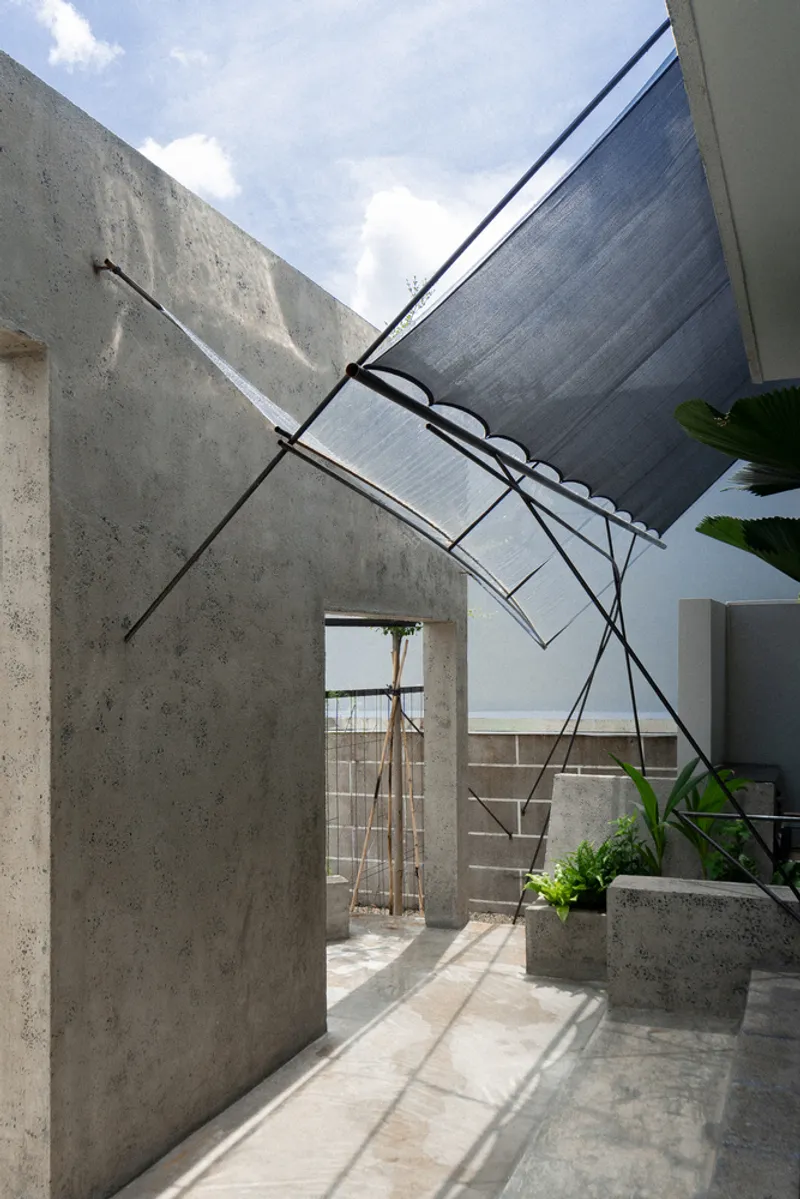 Corrugated metal canopy suspended above concrete walls in an open courtyard under midday sun