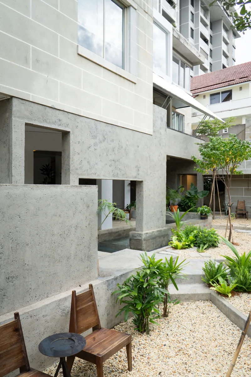 Concrete ground floor with framed openings below block masonry facade and rooftop plantings
