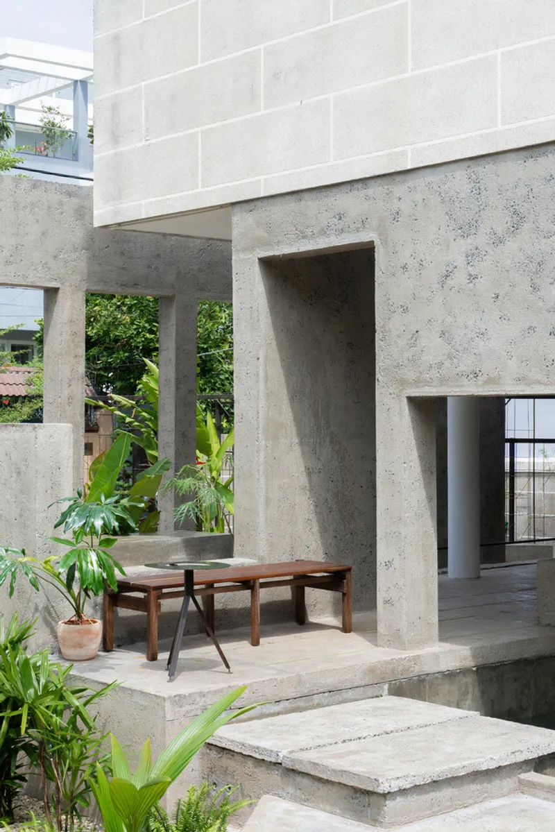 Concrete terrace with wooden bench and potted plants framed by heavy piers and textured walls